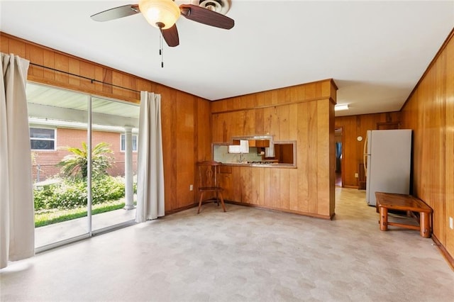 2209 Athania Pkwy, Metairie, LA 70001 - kitchen featuring freestanding refrigerator, wooden walls, brown cabinets, and ceiling fan