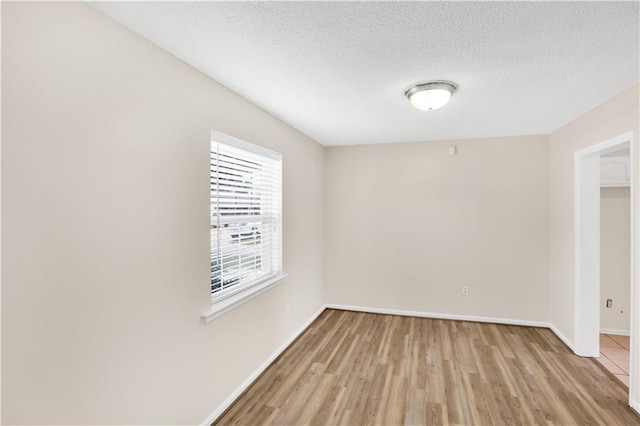 empty room featuring light wood-type flooring and a textured ceiling