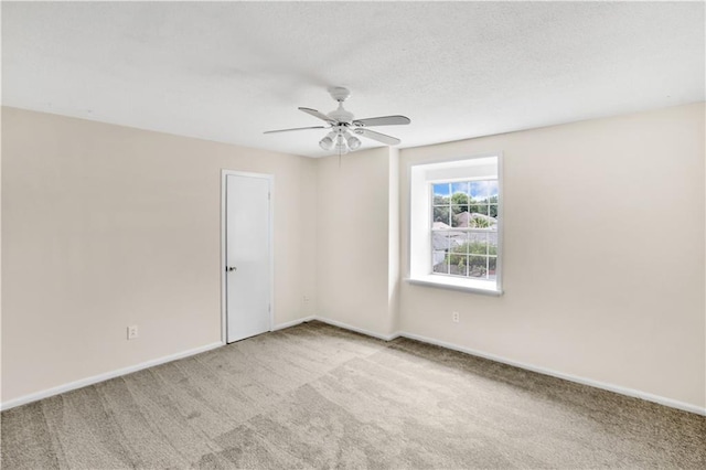 carpeted spare room featuring ceiling fan and baseboards