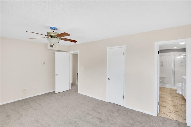 unfurnished bedroom with light colored carpet, ensuite bathroom, and ceiling fan