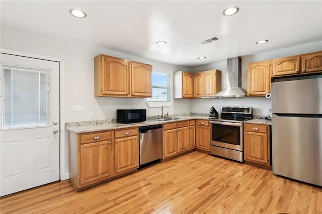 243 Carr Dr, Slidell, LA 70458 - kitchen with stainless steel appliances, wall chimney exhaust hood, light stone counters, light wood finished floors, and recessed lighting