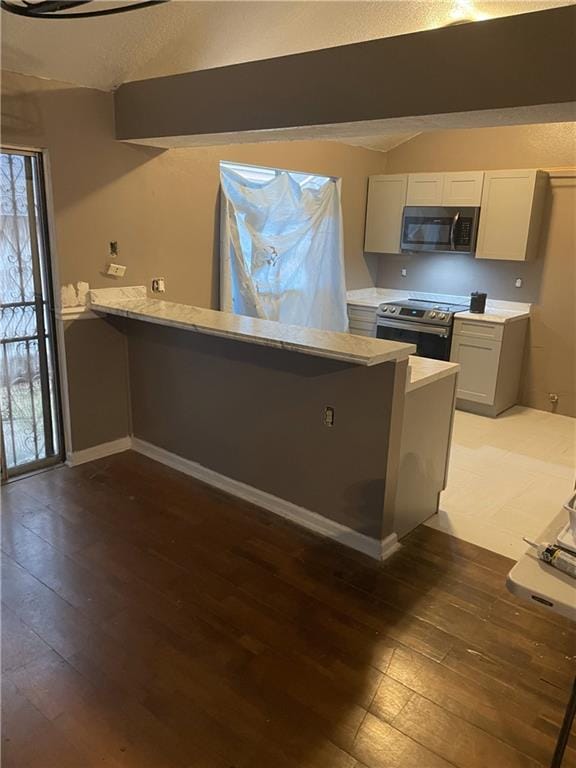 5531 New England Dr, New Orleans, LA 70129 - kitchen with vaulted ceiling, wood-type flooring, stainless steel electric stove, light countertops, and a peninsula