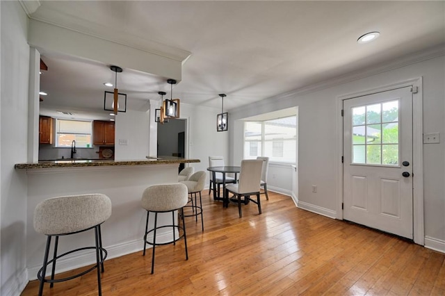 4043 S Inwood Ave, New Orleans, LA 70131 - kitchen featuring a kitchen bar, brown cabinets, crown molding, plenty of natural light, and light wood-type flooring