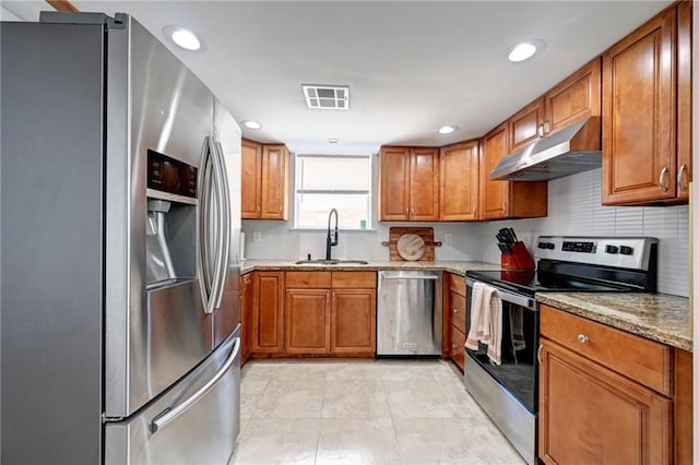 4043 S Inwood Ave, New Orleans, LA 70131 - kitchen with stainless steel appliances, under cabinet range hood, brown cabinetry, light stone countertops, and recessed lighting