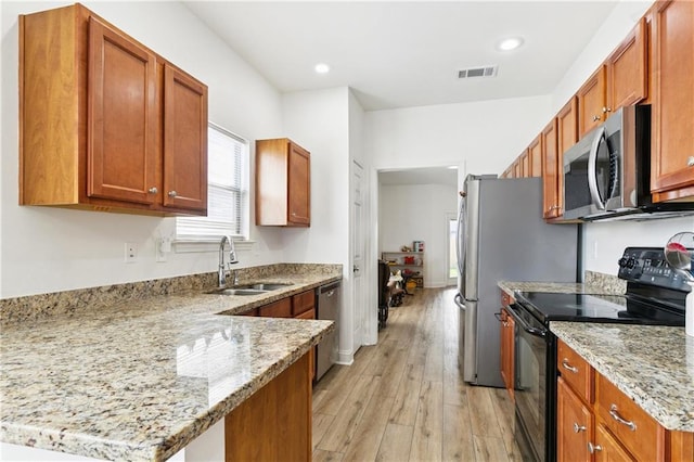 5233 Savannah Ln, Marrero, LA 70072 - kitchen featuring stainless steel appliances, light wood finished floors, light stone countertops, a peninsula, and brown cabinetry