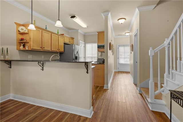 158 Emerald Oaks Dr, Covington, LA 70433 - kitchen with stainless steel fridge, dark countertops, a peninsula, a kitchen breakfast bar, and crown molding