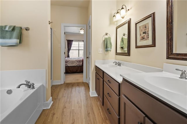 158 Emerald Oaks Dr, Covington, LA 70433 - ensuite bathroom with double vanity, wood finished floors, a garden tub, and ceiling fan