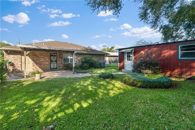 1139 Nursery Ave, Metairie, LA 70005 - back of property featuring a lawn, a patio, and brick siding