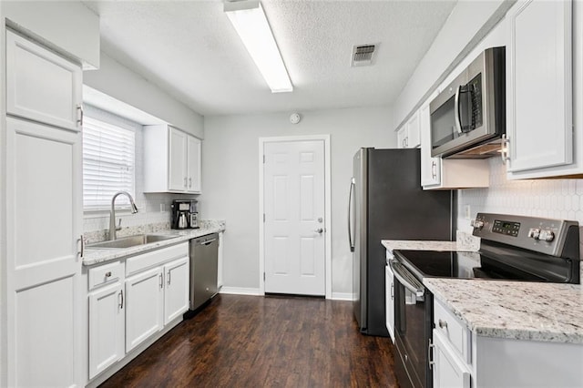 834 Mongrue St, Luling, LA 70070 - kitchen featuring appliances with stainless steel finishes, decorative backsplash, white cabinetry, a textured ceiling, and dark wood-type flooring