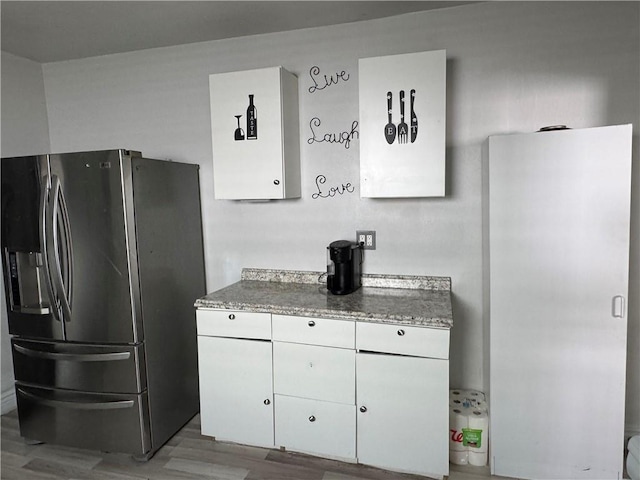 2903 Arlington St, Jefferson, LA 70121 - kitchen with stainless steel fridge with ice dispenser, white cabinetry, wood finished floors, freestanding refrigerator, and light stone counters
