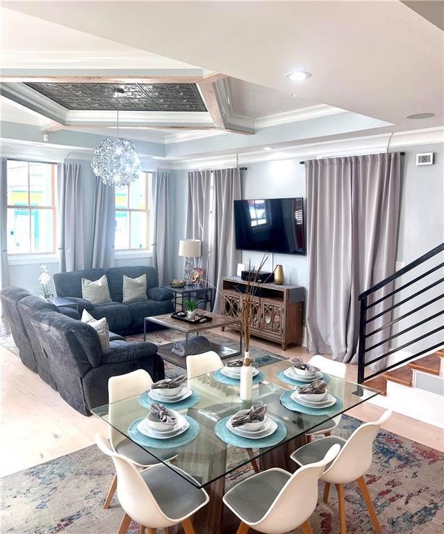 1515 St Ann St, New Orleans, LA 70116 - dining space with wood finished floors, crown molding, a chandelier, stairs, and coffered ceiling