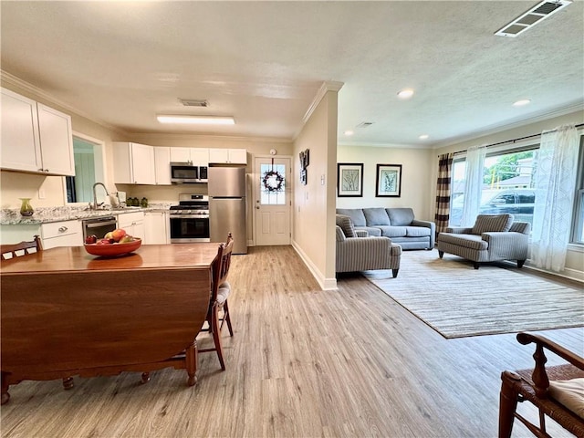 137 Diane Ave, River Ridge, LA 70123 - kitchen featuring stainless steel appliances, crown molding, light wood-type flooring, white cabinetry, and open floor plan