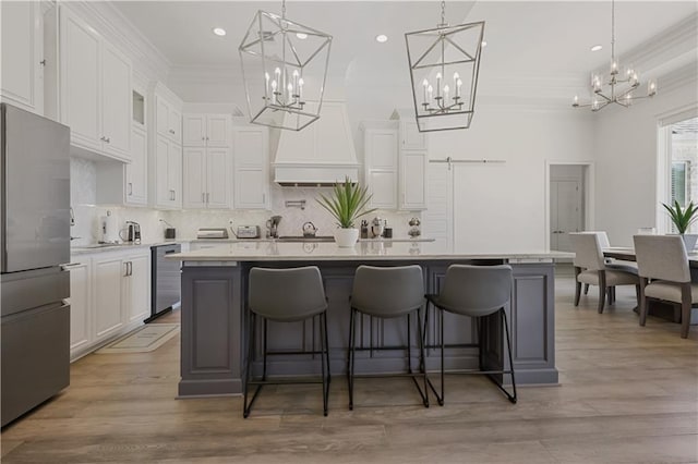 128 Juniper Ct, Mandeville, LA 70471 - kitchen with freestanding refrigerator, a chandelier, crown molding, white cabinets, and decorative backsplash