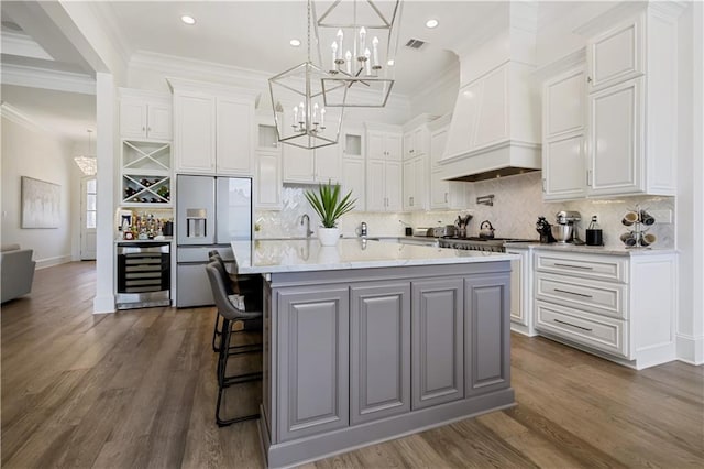 128 Juniper Ct, Mandeville, LA 70471 - kitchen with stainless steel fridge with ice dispenser, a chandelier, beverage cooler, white cabinets, and custom exhaust hood