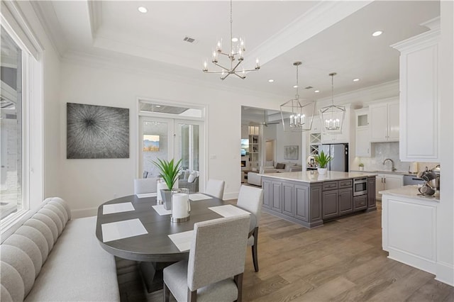 128 Juniper Ct, Mandeville, LA 70471 - dining room featuring a chandelier, light wood-style floors, crown molding, recessed lighting, and a raised ceiling