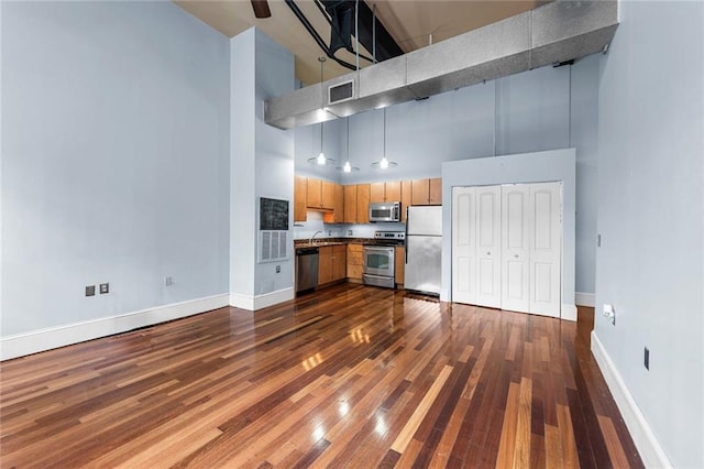 920 Poeyfarre St Unit 161, New Orleans, LA 70131 - kitchen featuring a towering ceiling, appliances with stainless steel finishes, dark wood finished floors, and dark countertops