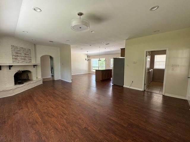 372 W 5th St, La Place, LA 70068 - unfurnished living room with a fireplace, dark wood-style floors, arched walkways, recessed lighting, and a chandelier