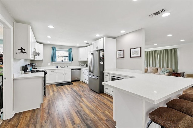 701 Mehle St, Arabi, LA 70032 - kitchen with stainless steel appliances, dark wood-type flooring, a peninsula, light countertops, and recessed lighting
