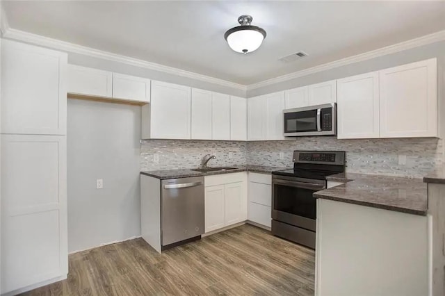 176 Meadowmoss Dr, Slidell, LA 70458 - kitchen featuring appliances with stainless steel finishes, white cabinetry, tasteful backsplash, wood finished floors, and crown molding