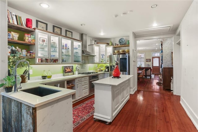 3705 Carondelet St, New Orleans, LA 70115 - kitchen with appliances with stainless steel finishes, wall chimney exhaust hood, open shelves, dark wood-style floors, and glass insert cabinets
