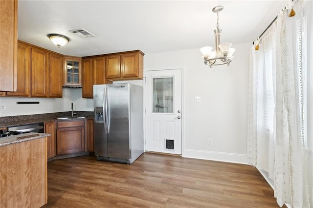 1620 Forshey St, Metairie, LA 70001 - kitchen featuring appliances with stainless steel finishes, brown cabinets, a chandelier, wood finished floors, and glass insert cabinets