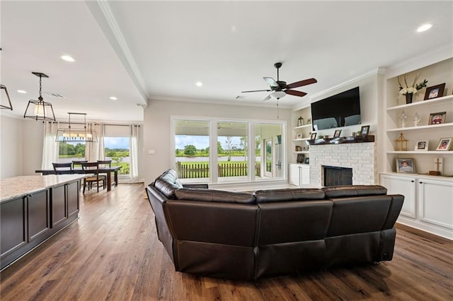 122 Highland Crest Dr, Covington, LA 70435 - living room featuring a ceiling fan, a brick fireplace, crown molding, dark wood-style flooring, and recessed lighting