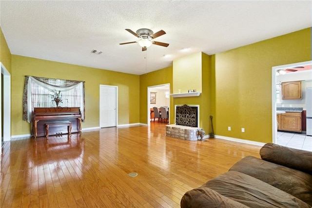 131 Asphodel Dr, Luling, LA 70070 - living room featuring a ceiling fan, light wood-type flooring, a fireplace with raised hearth, and a textured ceiling