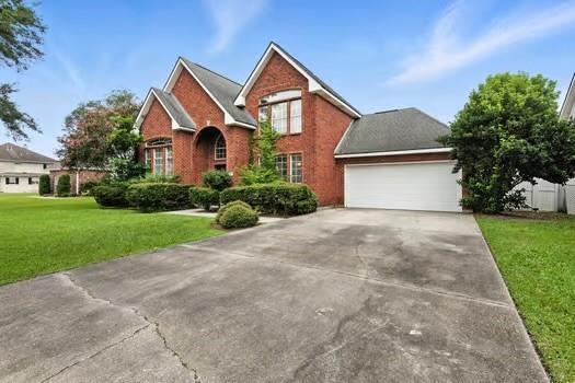 110 Woodchase Dr, Belle Chasse, LA 70037 - traditional-style house with concrete driveway, a garage, a front yard, and brick siding