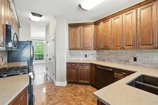 110 Woodchase Dr, Belle Chasse, LA 70037 - kitchen with appliances with stainless steel finishes, light countertops, backsplash, and brown cabinets
