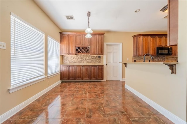 110 Woodchase Dr, Belle Chasse, LA 70037 - kitchen featuring black microwave, decorative backsplash, brown cabinetry, and decorative light fixtures