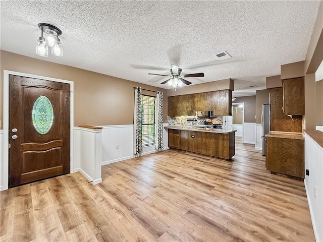 41449 N Charbonnet Rd, Ponchatoula, LA 70454 - kitchen featuring a peninsula, light wood-style floors, freestanding refrigerator, a textured ceiling, and light countertops
