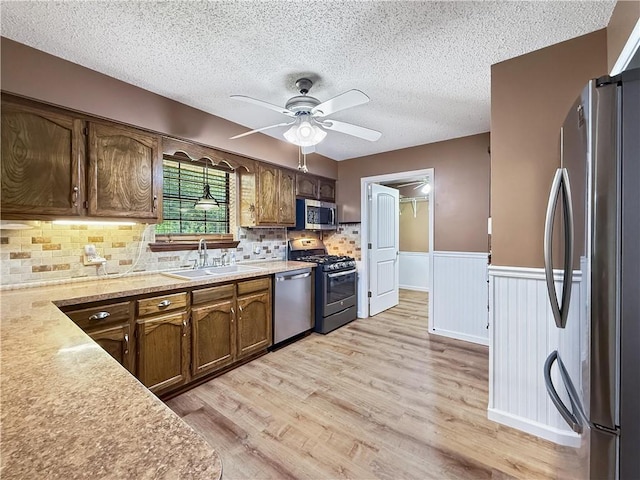 41449 N Charbonnet Rd, Ponchatoula, LA 70454 - kitchen featuring stainless steel appliances, a textured ceiling, light wood-style floors, light countertops, and wainscoting