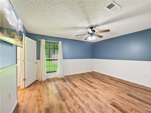 41449 N Charbonnet Rd, Ponchatoula, LA 70454 - unfurnished room with a wainscoted wall, wood finished floors, a textured ceiling, and a ceiling fan