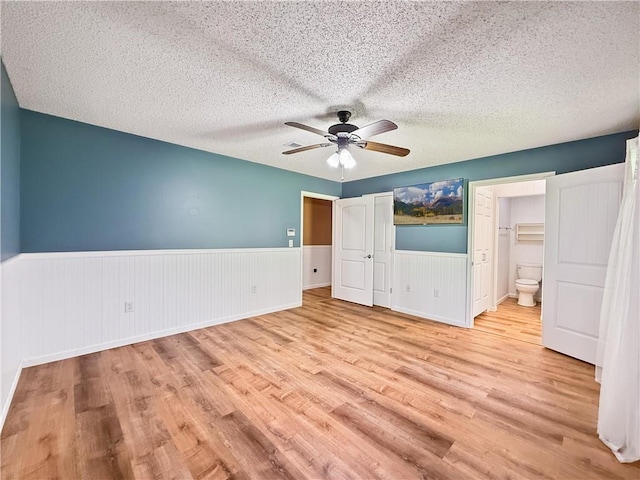 41449 N Charbonnet Rd, Ponchatoula, LA 70454 - unfurnished bedroom featuring wood finished floors, a wainscoted wall, a textured ceiling, ensuite bath, and a ceiling fan