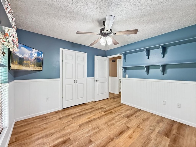 41449 N Charbonnet Rd, Ponchatoula, LA 70454 - unfurnished bedroom featuring a textured ceiling, wainscoting, wood finished floors, a closet, and a ceiling fan