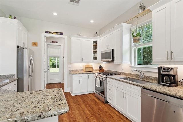 53131 S Bennett Rd, Independence, LA 70443 - kitchen with appliances with stainless steel finishes, white cabinets, light stone counters, wood finished floors, and glass insert cabinets