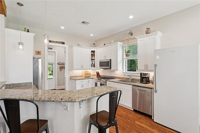 53131 S Bennett Rd, Independence, LA 70443 - kitchen with appliances with stainless steel finishes, a peninsula, a kitchen bar, glass insert cabinets, and light stone counters