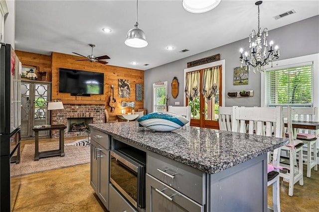 22101 Fletcher Rd, Ponchatoula, LA 70454 - kitchen with stainless steel microwave, concrete floors, gray cabinets, healthy amount of natural light, and wood walls