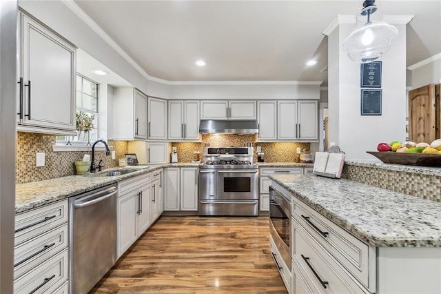 163 Tchefuncte Dr, Covington, LA 70433 - kitchen with appliances with stainless steel finishes, under cabinet range hood, light wood finished floors, ornamental molding, and light stone countertops
