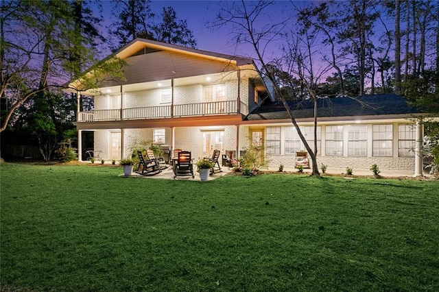 163 Tchefuncte Dr, Covington, LA 70433 - back of property at dusk featuring a balcony, a lawn, brick siding, and a patio