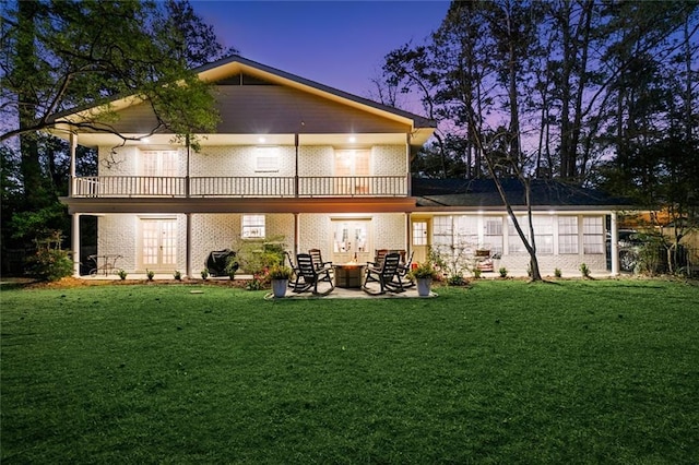 163 Tchefuncte Dr, Covington, LA 70433 - back of house at dusk with a patio area, a yard, a balcony, brick siding, and a fire pit