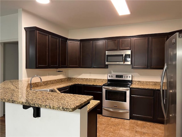 500 Buckthorne Pl, Covington, LA 70435 - kitchen featuring stainless steel appliances, a peninsula, dark brown cabinets, and light stone counters