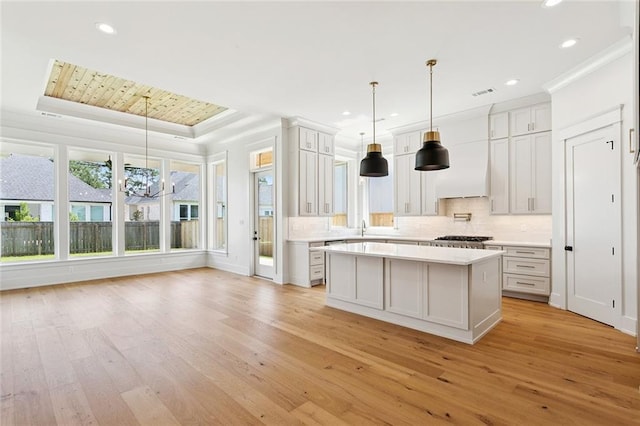 4233 Cypress Point Dr, Covington, LA 70433 - kitchen featuring a raised ceiling, light countertops, light wood-style flooring, backsplash, and recessed lighting