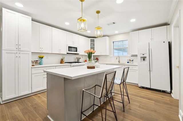 143 Vans Ln, Destrehan, LA 70047 - kitchen featuring white appliances, a kitchen breakfast bar, white cabinetry, backsplash, and recessed lighting