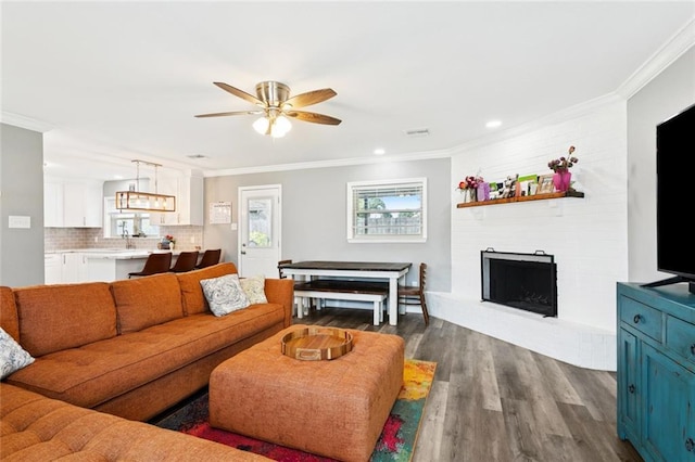 5924 Bellingham Pl, Metairie, LA 70003 - living room with ornamental molding, ceiling fan, dark wood finished floors, a large fireplace, and plenty of natural light