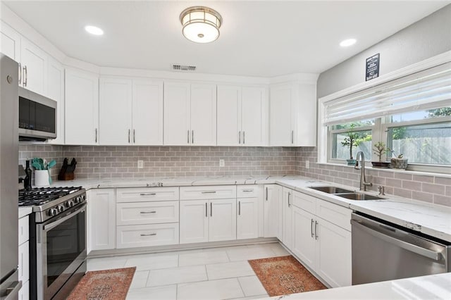 5924 Bellingham Pl, Metairie, LA 70003 - kitchen featuring stainless steel appliances, tasteful backsplash, white cabinets, light stone counters, and recessed lighting