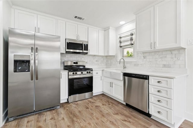 1112 Kent Ave, Metairie, LA 70001 - kitchen featuring appliances with stainless steel finishes, white cabinets, tasteful backsplash, light wood finished floors, and recessed lighting