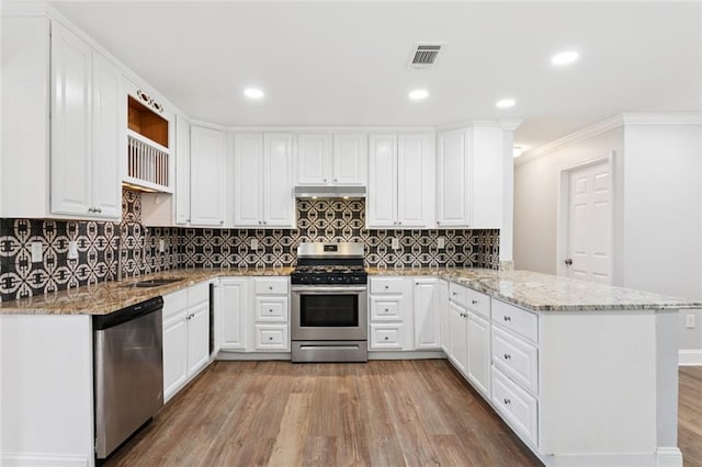 8021 Shirley St, Metairie, LA 70003 - kitchen featuring appliances with stainless steel finishes, a peninsula, light wood-style flooring, under cabinet range hood, and white cabinets