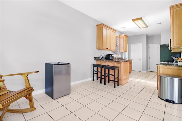 1022 Forest Ridge Loop, Pearl River, LA 70452 - kitchen with freestanding refrigerator, a peninsula, a breakfast bar, light brown cabinets, and light tile patterned floors