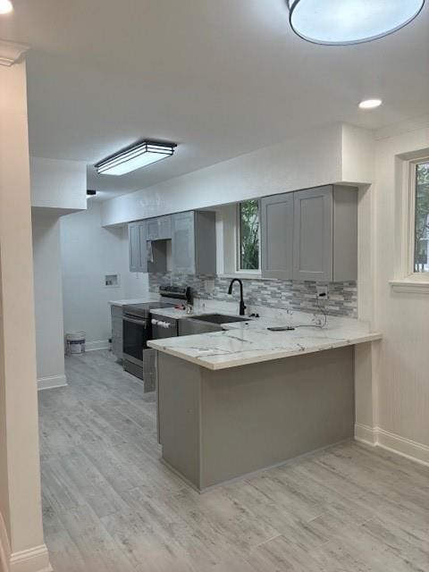 29 Snipe St, New Orleans, LA 70124 - kitchen with gray cabinetry, stainless steel electric range oven, light wood-type flooring, a peninsula, and decorative backsplash